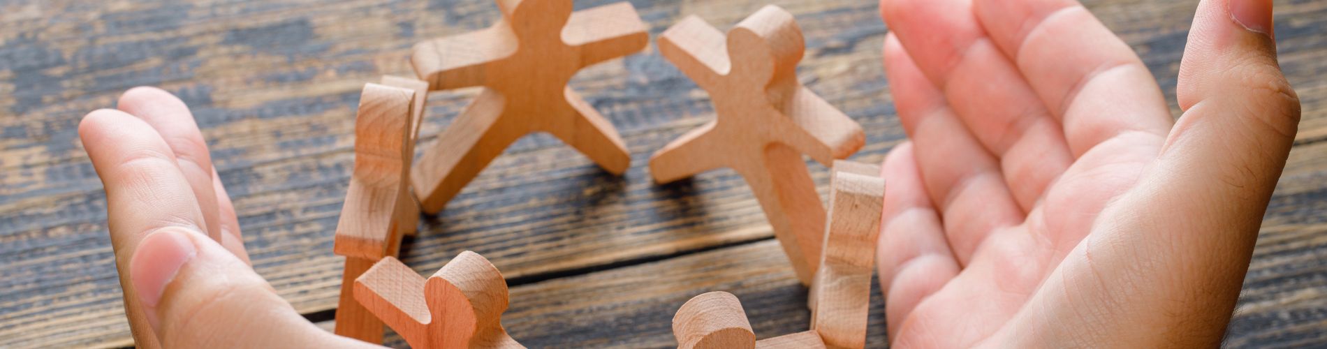 concetto-di-successo-di-affari-sulla-vista-di-legno-del-piano-d-appoggio-mani-che-proteggono-figure-in-legno-di-persone concetto-di-successo-di-affari-sulla-vista-di-legno-del-piano-d-appoggio-mani-che-proteggono-figure-in-legno-di-persone